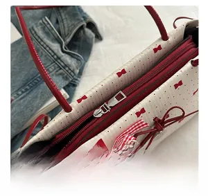Détail de motif nœud rouge sur sac blanc avec fermeture éclair et poignée rouge brillante