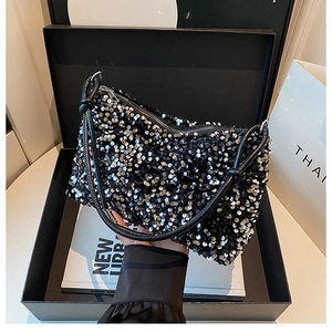 Close-up of glittery black sequin evening clutch bag in a luxury gift box packaging