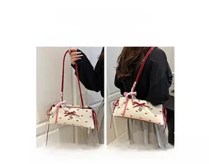 Sac baguette à nœuds avec breloque cœur porté à la main et à l'épaule pour femme