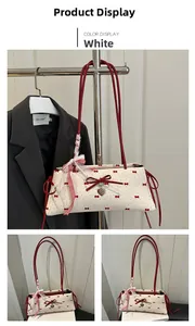 Gros plan d'un sac sous les aisselles blanc avec nœuds rouges et foulard à carreaux