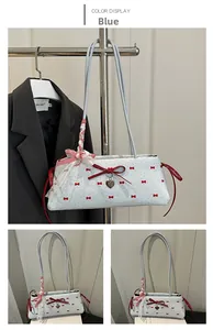 Détail du sac bandoulière bleu clair avec nœuds rouges et pendentif coeur métallique