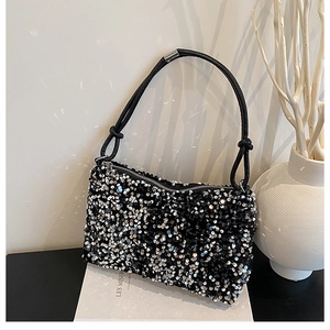Detail of a sparkling black sequin shoulder bag with leather handle and knot design