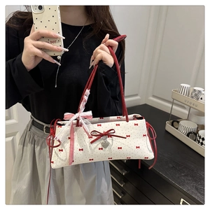 Détail du sac blanc avec motifs nœuds rouges, ruban dentelle et pendentif cœur métal