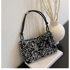 Macro view of sparkly black and silver sequins on shoulder bag with knot handle detail
