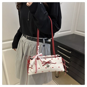 Détail du sac à bandoulière avec imprimé nœud rouge et pendentif cœur en dentelle