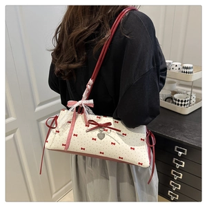 Détail du sac bandoulière à nœuds rouge et blanc avec pendentif cœur sur modèle