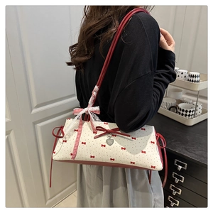 Détail d'un sac floral avec nœuds rouges, dentelle et pendentif en forme de cœur