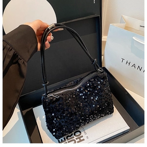 Close-up of black sequined crossbody bag with silver zipper in luxury gift box packaging