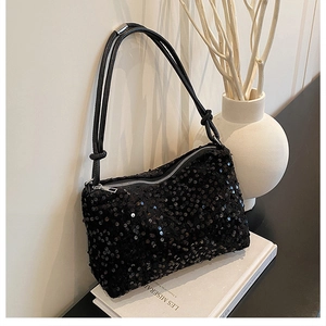 Detailed view of black sequin crossbody bag with slender shoulder straps and knotted detail