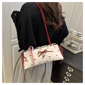 Détail du sac bandoulière en toile matelassée blanche avec nœuds rouges et pendentif cœur