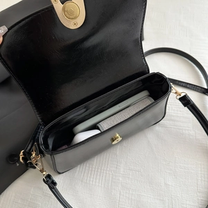 Petit sac bandoulière noir en similicuir avec boucle dorée montrant la capacité intérieure
