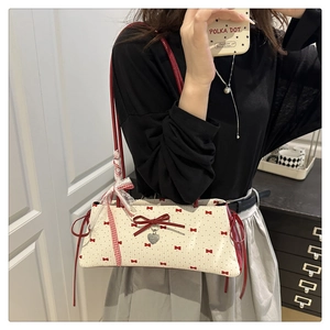 Vue détaillée du sac à bandoulière crème avec motif nœuds rouges et bordure dentelle