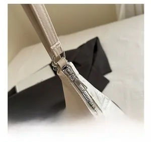 Dettaglio della cerniera in metallo argento e pelle beige di una borsa sottobraccio