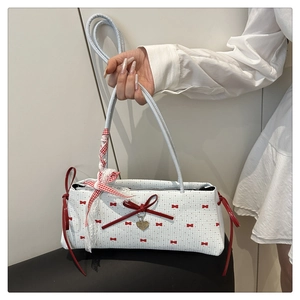 Détail du sac à main blanc avec pois rouges, nœuds en soie et pendentif cœur doré