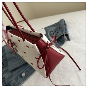 Vue détaillée du sac à main avec imprimé nœud rouge et laçage latéral décoratif