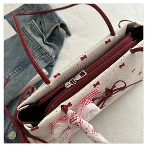 Détails de la fermeture éclair rouge et du nœud sur le sac à bandoulière crème