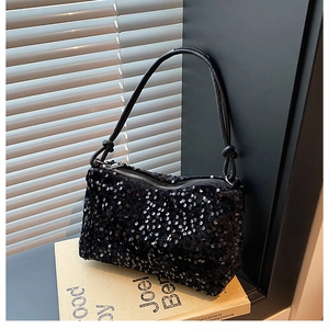 Detail of shimmering black sequin handbag with slim shoulder strap on vintage book decor