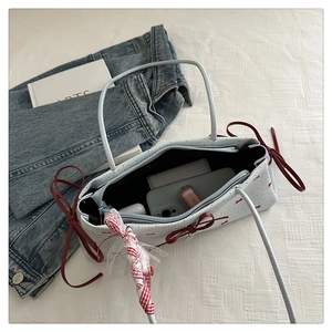 Détail d'un sac à bandoulière chic avec nœuds rouges et espace de rangement intérieur net