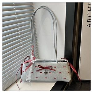 Détail du sac bandoulière bleu à pois avec nœud en cuir rouge et pendentif en cœur