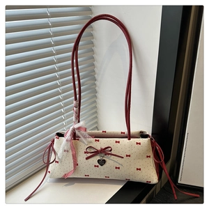 Détail du sac à bandoulière crème avec imprimés nœuds rouges et rubans en dentelle