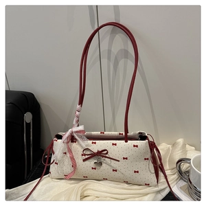 Détail de nœuds rouges sur sac blanc avec pendentif en cœur et ruban décoratif élégant