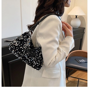 Detailed close-up of a black sequin hobo bag worn with a white blazer for a chic look