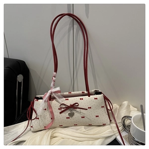 Détail du sac crème avec imprimés nœuds rouges, pendentif cœur et ruban en dentelle