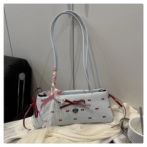 Détail du sac bleu clair orné d'un nœud rouge et d'un pendentif en forme de cœur