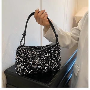 Detail of shimmering black and silver sequins on crossbody bag with knotted handle