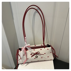 Détail du sac crème avec imprimé nœuds rouges, pendentif cœur et ruban en dentelle