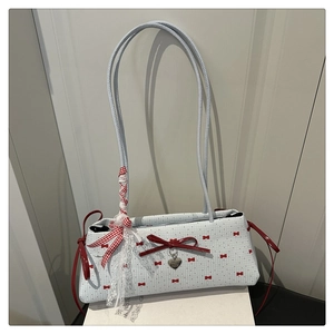 Détail du sac à bandoulière bleu à carreaux avec nœuds rouges et pendentif cœur
