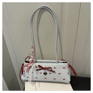 Détail du sac à bandoulière bleu clair avec imprimés nœuds rouges et pendentif cœur