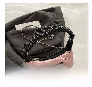 Detail of pink pleated handbag featuring black bow decoration and metallic chain strap
