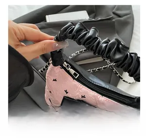 Detail of smooth silver zipper and pink jacquard fabric with black bow decoration