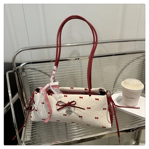 Vue détaillée du sac baguette crème avec motifs nœuds rouges et dentelle sur l'anse