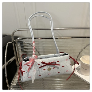 Détail du sac à main bleu clair à nœuds rouges avec pendentif cœur sur une étagère