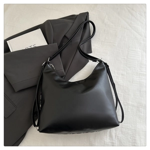 Detail of a chic black PU leather hobo bag with adjustable strap on textured fabric