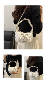 Close-up of white jacquard bow bag with heart pendant and silver chain strap