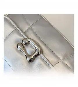 Détails de la texture matelassée argentée et boucle en métal liquide sur le sac