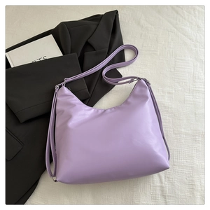 Detail shot of the purple crescent-shaped shoulder bag with adjustable strap and smooth finish