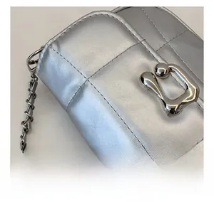 Détail du sac bandoulière argenté avec texture matelassée et fermoir métallique unique