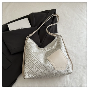 Detail view of jacquard hobo bag with silver geometric patterns and cream leather pocket