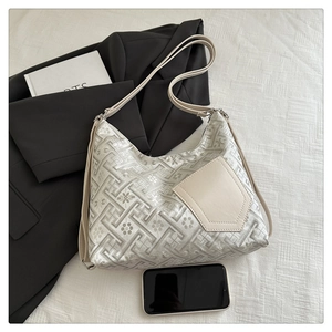 Close-up of hobo bag featuring silver floral embroidery and beige leather pocket detail