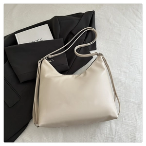 Detail shot of a cream white hobo shoulder bag with smooth faux leather and silver hardware