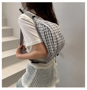 Detail of grey gingham corduroy chest bag with adjustable strap worn by a model