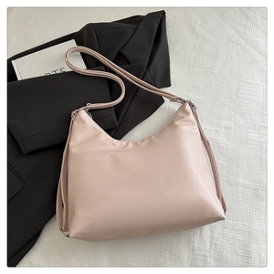 Flat lay of pink PU leather tote bag with side zippers on white textured fabric
