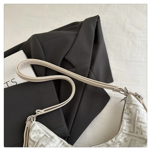 Detail of cream jacquard fabric texture and leather strap on a chic underarm bag
