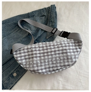 Close-up of gray plaid crossbody bag featuring white floral embroidery and nylon strap
