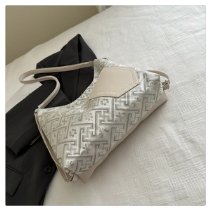Detailed close-up of Chinese embroidery patterns on a chic beige jacquard shoulder bag