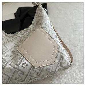 Macro view of geometric jacquard fabric and leather stitching on the Chinese style handbag